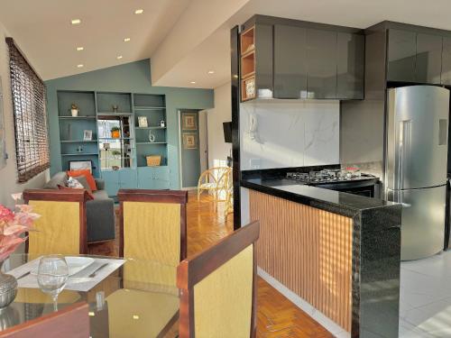 a kitchen and living room with a table and a refrigerator at Cobertura moderna no centro de Nova Friburgo in Nova Friburgo