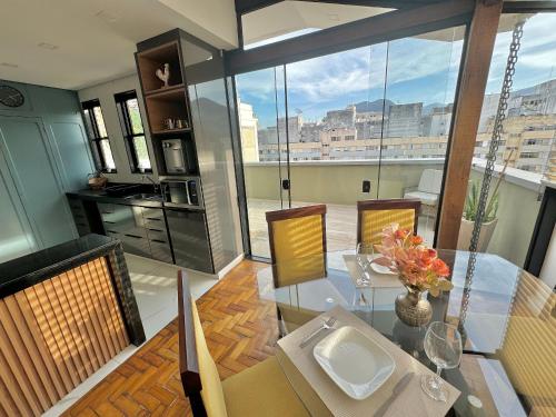 a dining room with a glass table and a large window at Cobertura moderna no centro de Nova Friburgo in Nova Friburgo