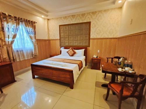 a bedroom with a bed and a table in it at Khách Sạn Tường Vy in An HÃ²a
