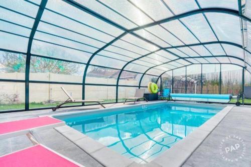 une piscine intérieure avec un toit en verre dans l'établissement maison avec piscine chaufée couverte d'avril à fin octobre, à Ranville