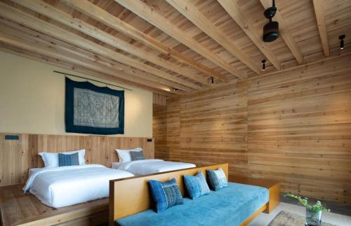two beds in a room with wooden walls at The Well House in Jiayi
