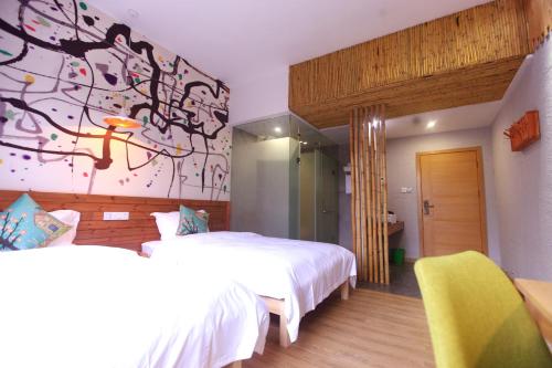 a bedroom with two beds and a painting on the wall at Zhangjiajie Forest Park Youth Hostel in Zhangjiajie