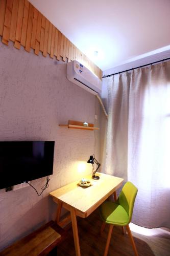 a room with a table and a television and a green chair at Zhangjiajie Forest Park Youth Hostel in Zhangjiajie