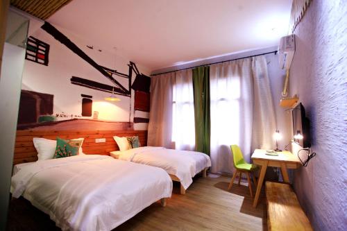 a bedroom with two beds and a desk and a window at Zhangjiajie Forest Park Youth Hostel in Zhangjiajie