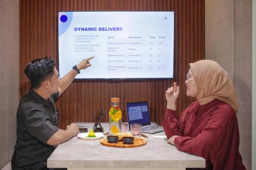 a man and a woman sitting at a table with a presentation at IB23 Inn Boutique Hotel in Bandung