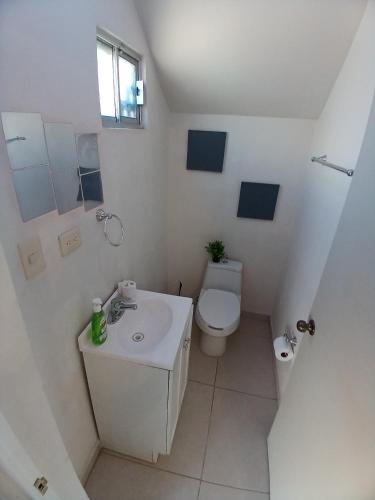 a white bathroom with a toilet and a sink at Vivienda completa 2 plantas, y privada con acceso controlado in Hermosillo