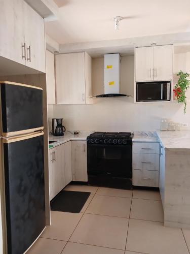 a kitchen with white cabinets and a black refrigerator at Vivienda completa 2 plantas, y privada con acceso controlado in Hermosillo