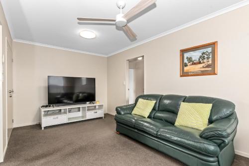 a living room with a green leather couch and a flat screen tv at Magical Waipu - Central Family Holiday Home in Waipu