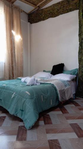 a bedroom with a bed with a green blanket at Casa Pórticos del Pedregal in Ráquira
