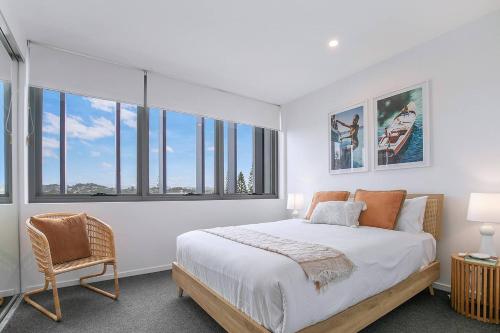 una camera da letto con un letto, una sedia e finestre di Starlit Palms - Chic Poolside Haven by the Beach a Gold Coast