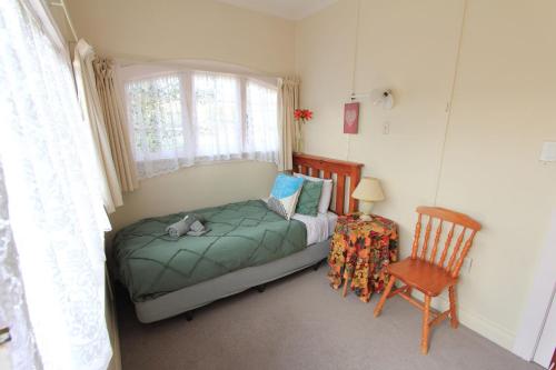 a small bedroom with a bed and a chair at The southernmost home in the world in Invercargill