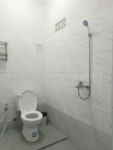 a white bathroom with a toilet and a shower at Kubu Alit Homestay Pandawa in Nusa Dua