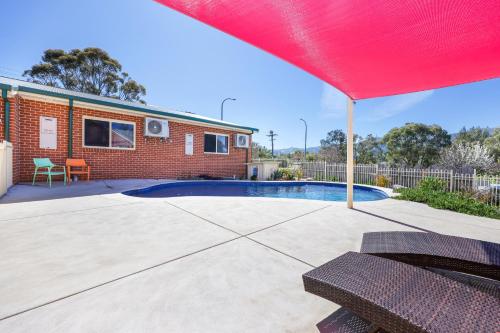 a house with a swimming pool and a red umbrella at Roseville Motel and Apartments in Tamworth