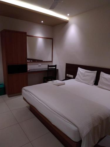 a bedroom with a large bed and a flat screen tv at Sri bhavan residency in Palakkad