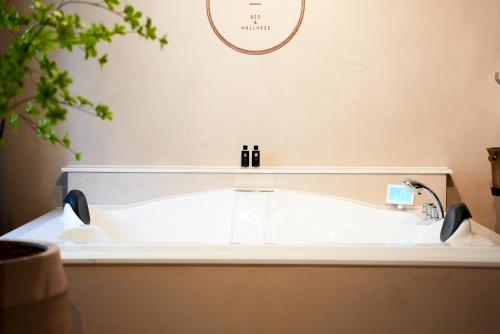 a bath tub in a bathroom with a clock on the wall at The Lodge Bed & Wellness Oisterwijk Sauna, Jacuzzi, Luxury in Moergestel