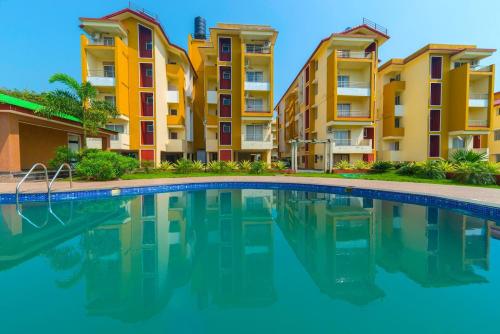 a swimming pool in front of some apartment buildings at FabHotel Ocean View Apartment - Nr Dabolim Airport in Old Goa