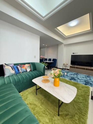 a living room with a green couch and a table at Miq Asoke 5BR Sukhuvit15 in Makkasan