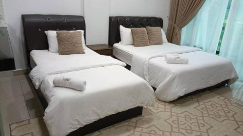 a bedroom with two beds with white sheets at HASSMA Studio Apartment at Kompleks Mutiara GM in Gua Musang
