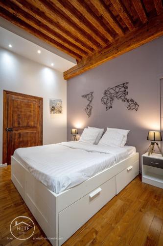 - un lit blanc dans une chambre dotée d'un plafond en bois dans l'établissement L'écrin de Chambéry, cœur de centre ville, calme et espace, à Chambéry