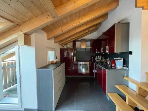 a large kitchen with red cabinets in a room at Stay in the Heart of Wallis in Leuk