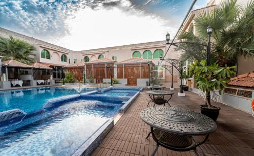 a swimming pool with a table next to a building at Al Dar Inn Hotel Apartment in Ras al Khaimah