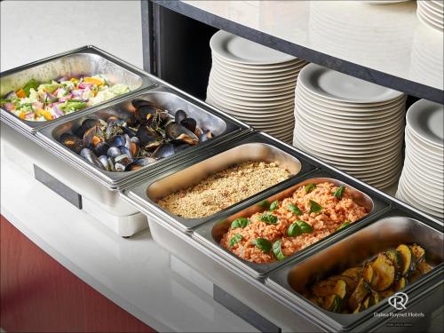 two trays of food on a counter with plates at Daiwa Roynet Hotel Yokohama-Koen in Yokohama