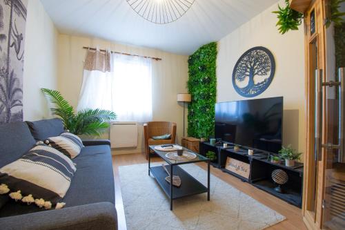 ein Wohnzimmer mit einem blauen Sofa und einem Fernseher in der Unterkunft Wood & Sea I Sauna & Hyper centre in Crozon