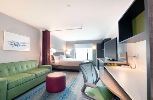 a hotel room with a green couch and a bed at Home2 Suites By Hilton Quebec City in Quebec City