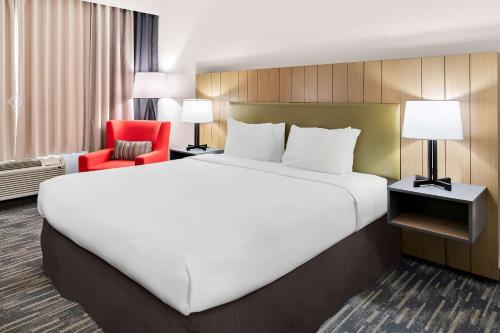 a hotel room with a large bed and a red chair at Country Inn & Suites by Radisson, Columbia Airport, SC in Columbia