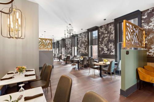 a dining room with tables and chairs and chandeliers at Tygart Hotel, an Ascend Collection Hotel in Elkins