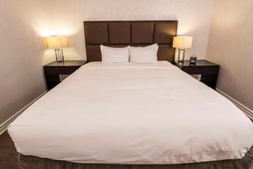 a large white bed in a hotel room with two lamps at Chateau Cartier Hotel & Resort, an Ascend Collection Resort in Gatineau