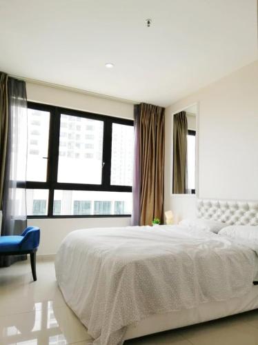 a white bedroom with a large bed and a blue chair at Paris Cozy House in Shah Alam