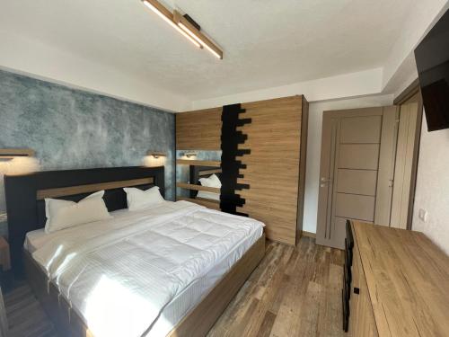 a bedroom with a large white bed and a wooden floor at Transylvanian Views in Peştera