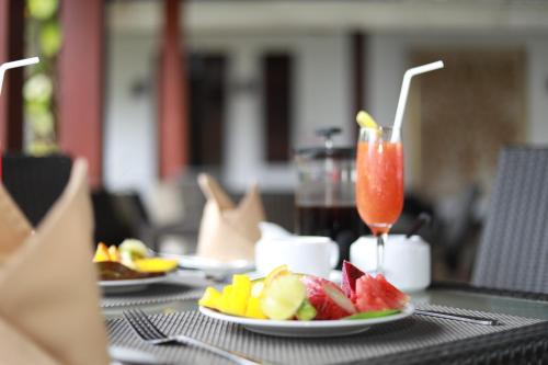 a table with plates of fruit and a drink at Swanee Grand in Negombo