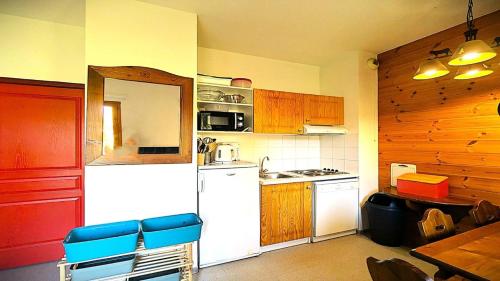 La cuisine est équipée d'un réfrigérateur blanc et de placards en bois. dans l'établissement Résidence Le Palatin - APPARTEMENT EN REZ DE CHAUSSEE AU PIED DES PISTES - 4/6 PERS MAE-9021, à Pelvoux