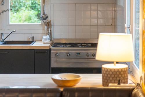 a kitchen with a table with a lamp and a stove at Maison Valérie à 1km plage in Trégunc