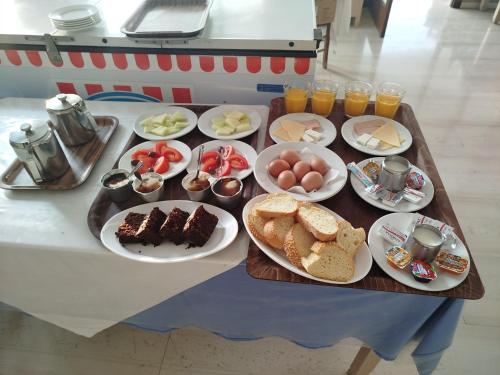 una mesa con una bandeja de alimentos y bebidas para el desayuno en Hotel 3 Adelfia, en Agia Marina Aegina
