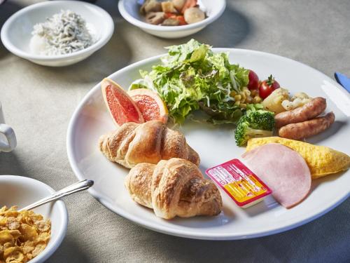 a white plate of food with croissants and other foods at Hakuba Alps Hotel in Otari