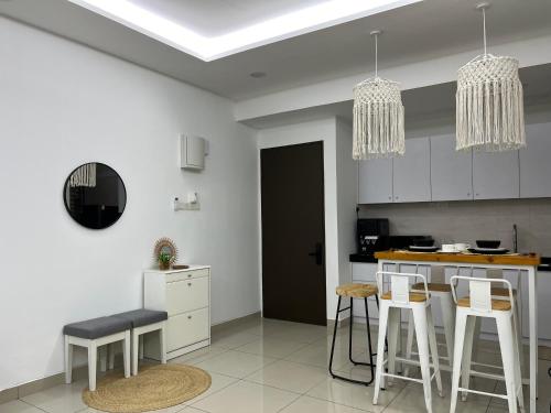 a kitchen with white cabinets and bar stools at Boho Bliss Escape, near Sunway Pyramid, Subang Jaya in Subang Jaya