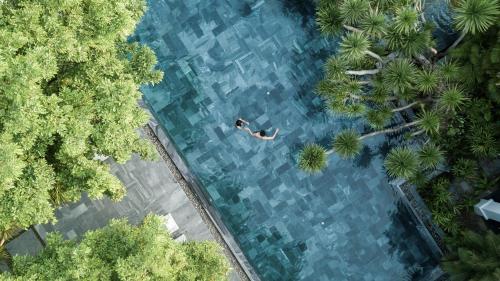 a person swimming in a pool of water with trees at TIA Wellness Resort - Spa Inclusive in Da Nang