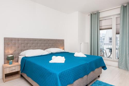 sypialnia z niebieskim łóżkiem i ręcznikami na nim w obiekcie Apartamenty Aquamarina by Noclegi Renters w Świnoujściu