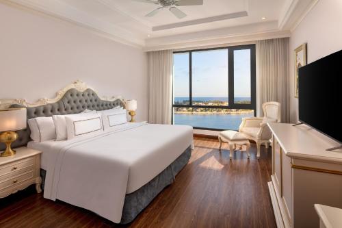 a bedroom with a large bed and a large window at Melia Vinpearl Quang Binh in Dong Hoi