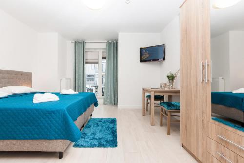 a bedroom with two beds and a table and a desk at Apartamenty Aquamarina by Renters in Świnoujście