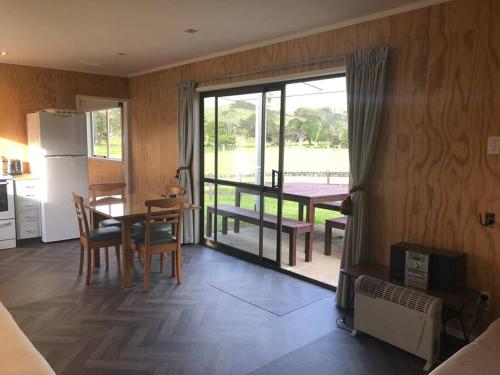 a kitchen with a table and a dining room with a view at Leon's Bach, Waikawau Bay in Port Charles