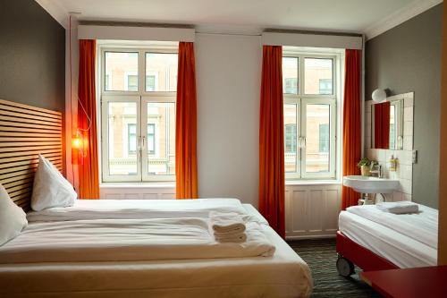 a bedroom with two beds and two windows at Annex Copenhagen in Copenhagen