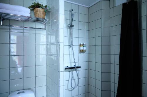 a white tiled shower with a hose in a bathroom at Annex Copenhagen in Copenhagen