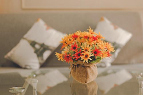 a vase filled with orange and red flowers on a table at AU Place Hotel in Loei