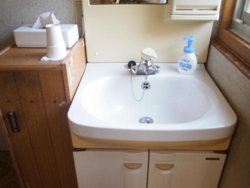 a bathroom with a sink and a bottle of soap at Shingu Guest House SOU 別館 in Shingu