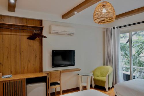 a bedroom with a bed and a tv and a chair at Cheers Hostel Hanoi in Hanoi