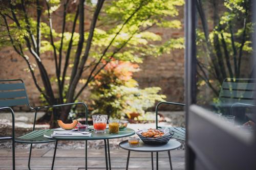 two tables with food on them on a patio at Cour du Corbeau Hotel Strasbourg - MGallery Collection in Strasbourg